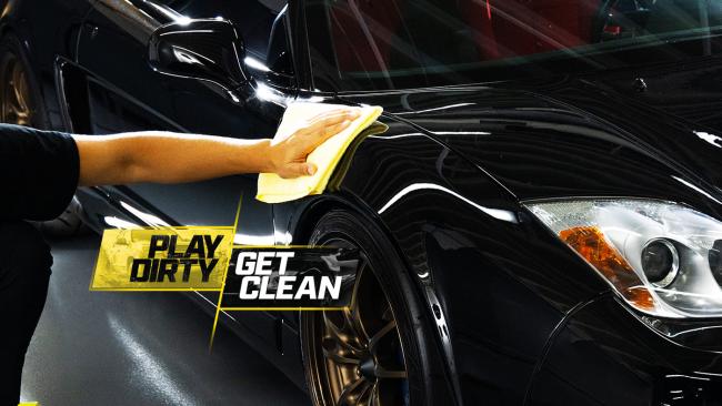 Hand wiping down a black sports car - Play Dirty Get Clean